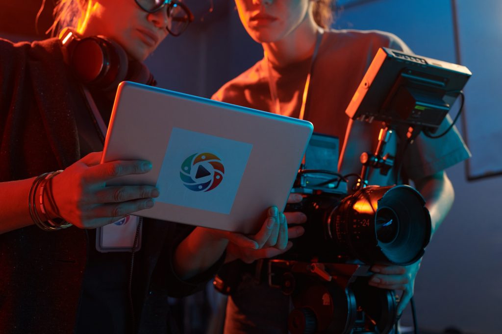 Video production crew reviewing footage on a tablet, showcasing collaborative work in a professional setting with a camera and lighting equipment.