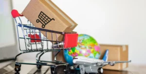 Shopping cart with boxes, globe, and airplane model, symbolizing e-commerce and global supply chain strategies.