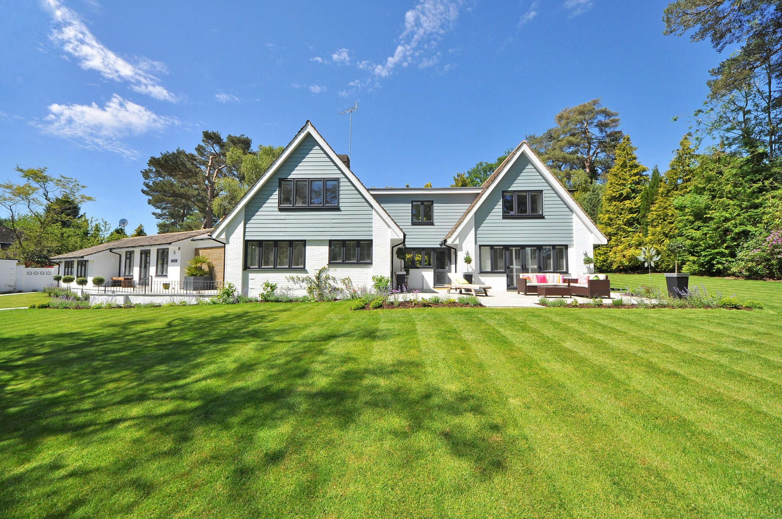 Modern house with landscaped lawn and outdoor living space, showcasing quality design for landscaping services.